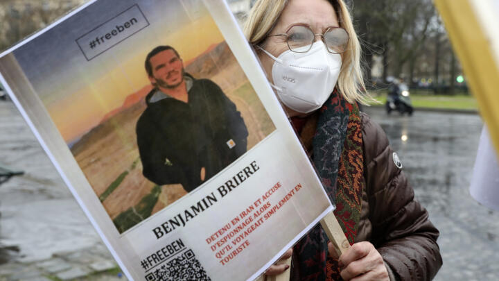 A woman holds a photo of Benjamin Brière, a Frenchman detained in Iran, during a rally in Paris on January 8, 2022.